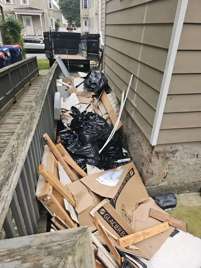 Driveway filled with cardboard boxes and trash bags before junk removal near Wareham